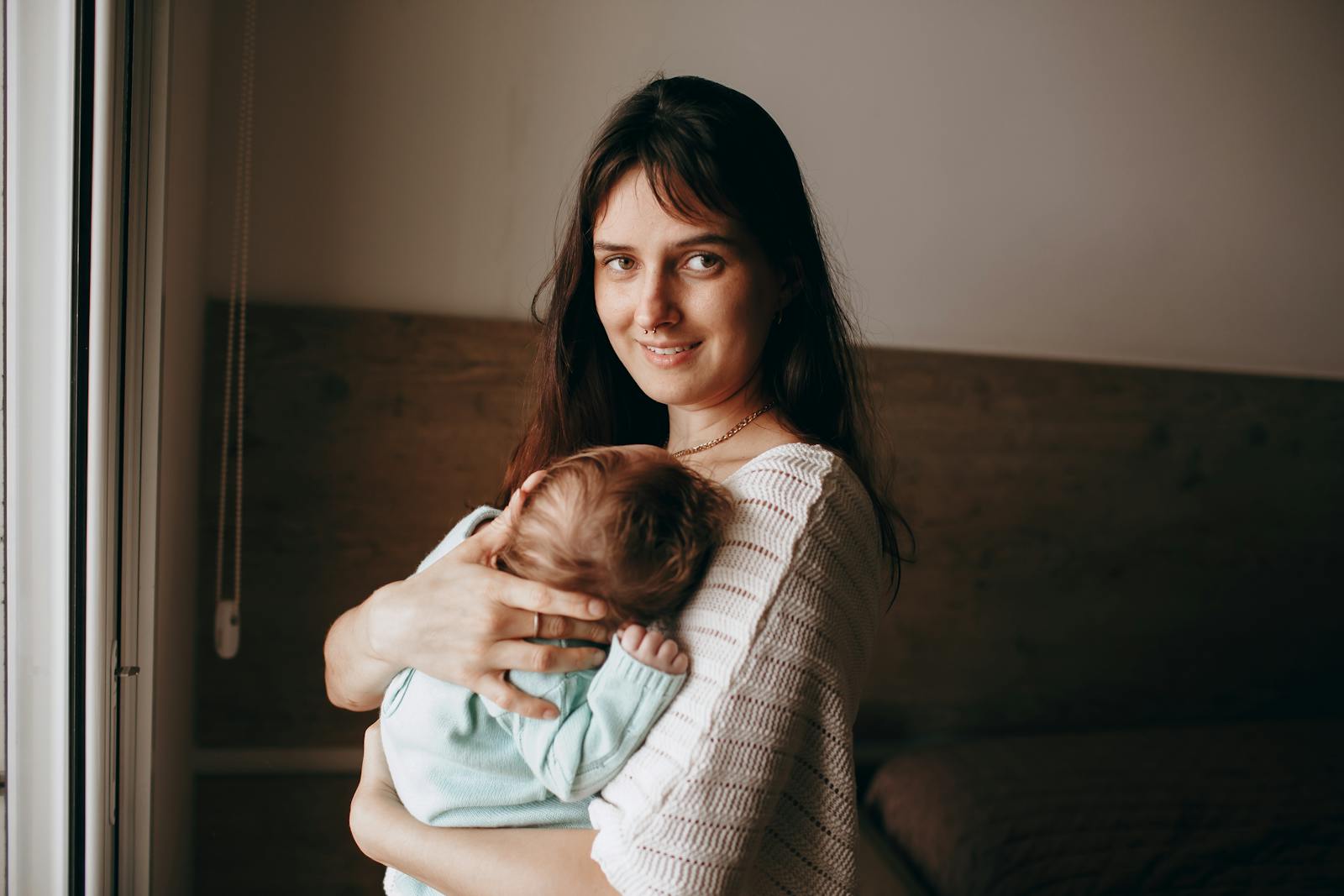 A mother gently holding her newborn beside a car, Northern Beaches